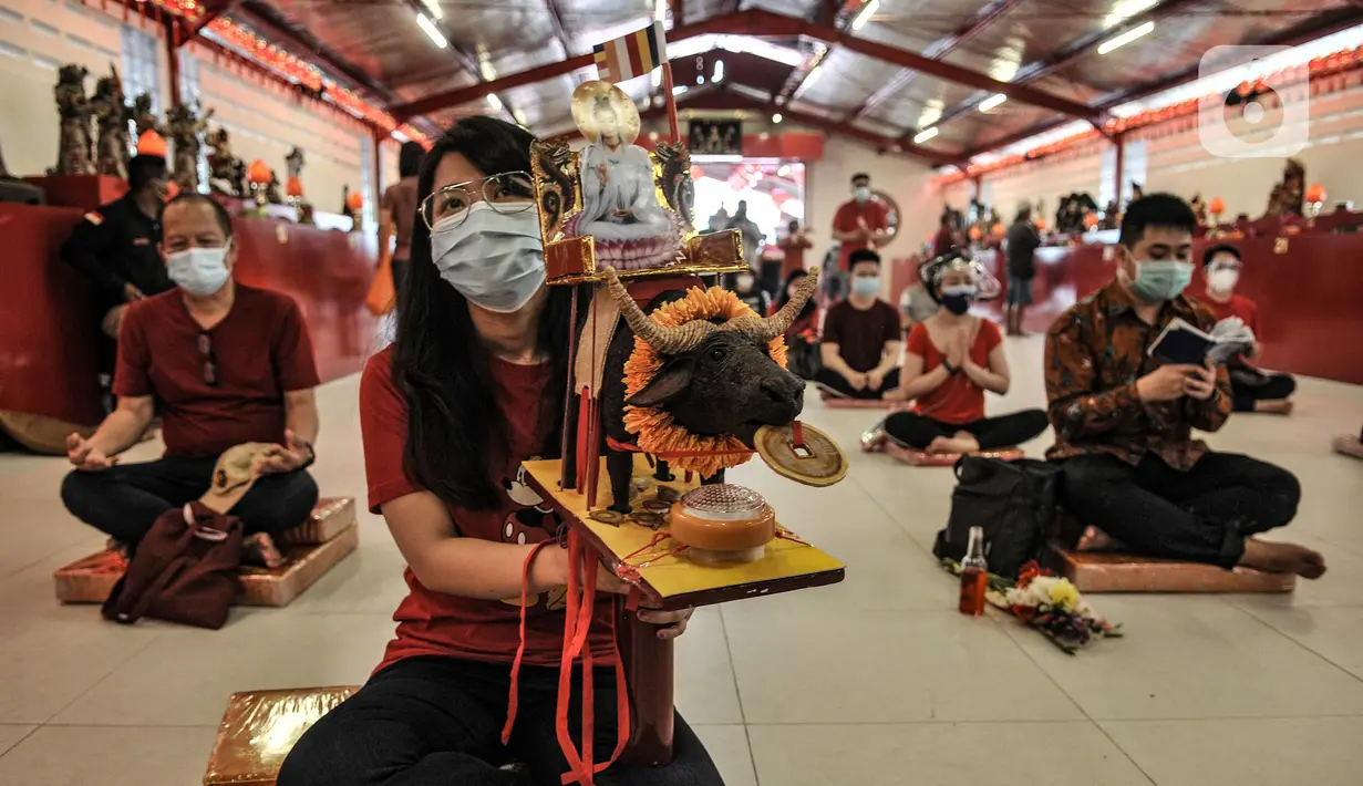 Warga keturunan Tionghoas membawa patung simbol kerbau logam yang merupakan shio Tahun Baru Imlek 2572 di klenteng kawasan Petak Sembilan, Glodok, Jakarta, Kamis (11/2/2021). Pembatasan waktu sembahyang malam Imlek kali ini sebagai langkah mencegah penyebaran COVID-19. (merdeka.com/Iqbal S. Nugroho)