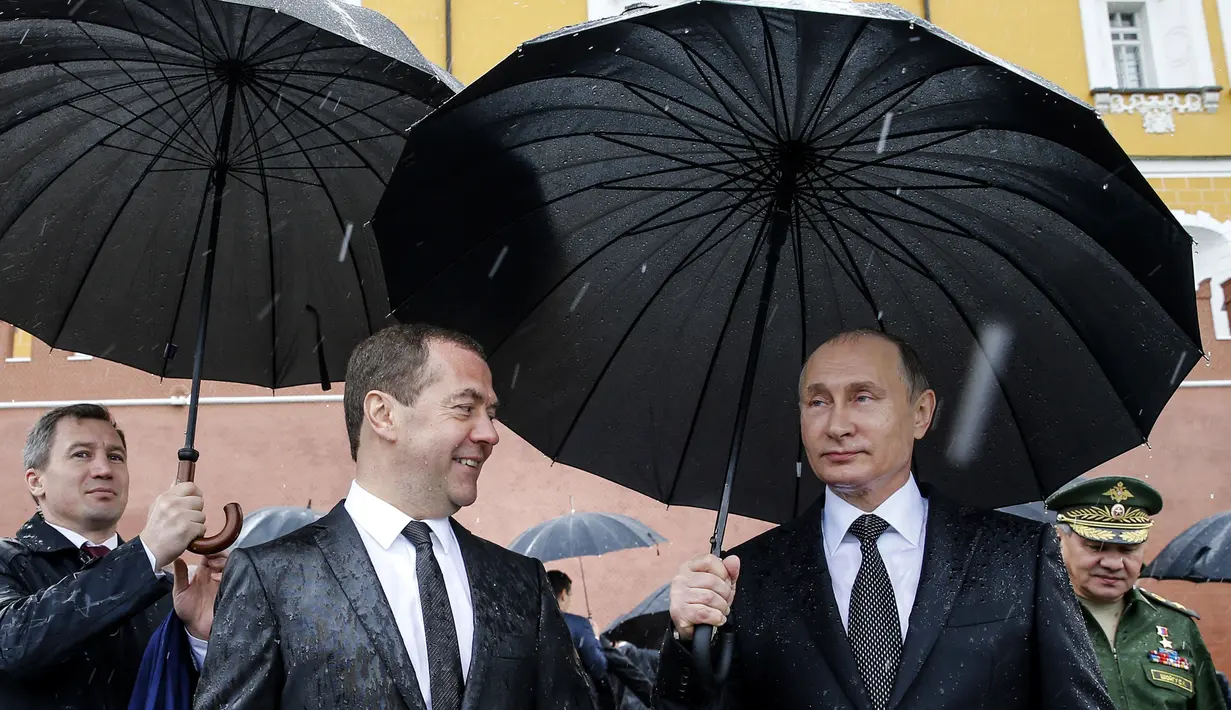 Presiden Rusia Vladimir Putin berbincang dengan PM Rusia Dmitry Medvedev sebelum memimpin upacara kehormatan untuk memperingati invasi Nazi Jerman pada 1941 di Benteng Kremlin di Moskow, Kamis (22/6). (Alexei Druzhinin/Sputnik, Kremlin Pool Photo via AP)