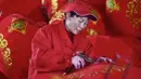 Seorang pekerja membuat lentera merah menjelang perayaan Tahun Baru Imlek 2020 di sebuah pabrik di Wuyi, China, Kamis (26/12/2019). Beberapa keunikan pada tradisi perayaan Imlek yang masih dijalani warga Tionghoa adalah menggantung lentera merah. (Photo by STR / AFP)