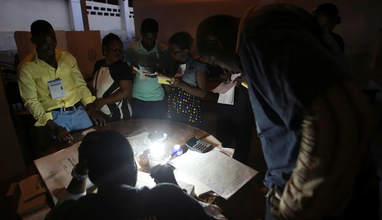 Para petugas pemilu bekerja, menghitung jumlah suara di sebuah Tempat Pengumutan Suara (TPS) di Port-au-Prince, Haiti (20/11). Pemilu ini tertunda akibat bencana alam dan ketidakstabilan politik yang terjadi di Haiti. (Reuters/Jeanty Junior Augustin)