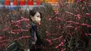 Seorang wanita membeli tanaman dan bunga pada hari pembukaan pasar bunga di Hong Kong (16/1/2023). Tahun Baru Imlek tahun ini jatuh pada tanggal 22 Januari 2023. (AFP/Peter Parks)