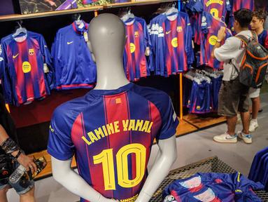 Pengunjung memilih jersey baru bernomor punggung 10 dari penyerang Barcelona asal Spanyol, Lamine Yamal di toko resmi FCB di Barcelona. (AFP/Manaure Quintero)