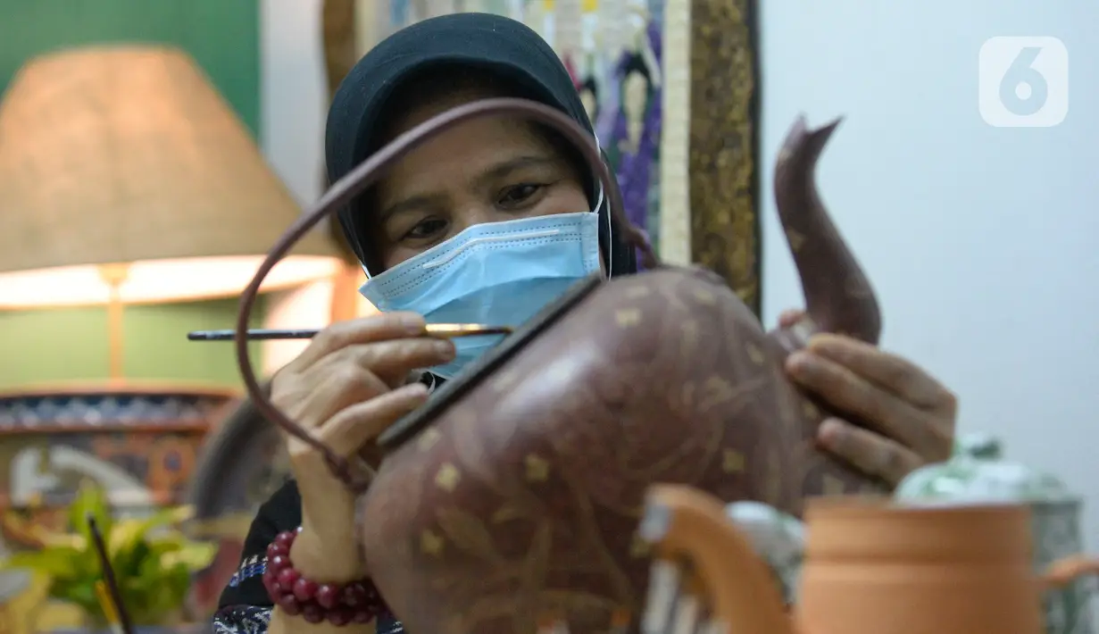 Perajin batik lukis ketel Nova Muhidir menyelesaikan lukisan batik di Studio Daroolang, Bintara, Tangerang Selatan, Banten, Rabu (2/12/2020). Lukisan ketel batik jadul khas nusantara di teko tempat air minum tersebut dijual dengan harga Rp 150 ribu hingga Rp 2,5 juta. (merdeka.com/Dwi Narwoko)
