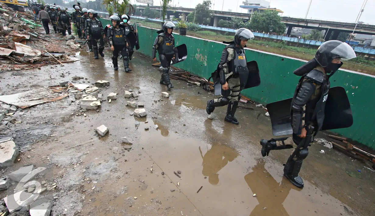 Petugas kepolisian saat berjaga di kawasan prostitusi Kalijodo, Jakarta Utara, Senin (29/2). Dalam hitungan jam, puluhan bangunan di kawasan tersebut mulai rata dengan tanah serta menjadi tontonan warga. (Liputan6.com/Immanuel Antonius)