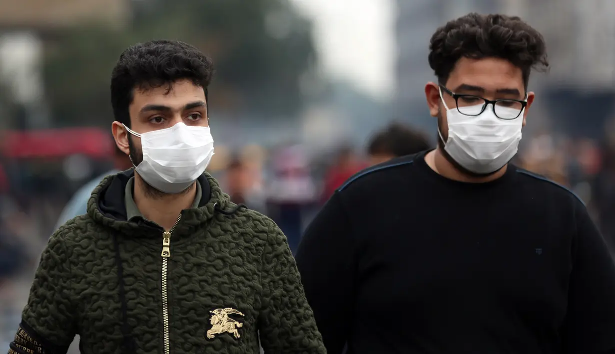 Dua pria mengenakan masker di sebuah jalan di Baghdad, Irak, (25/2/2020). Irak mengumumkan empat kasus baru COVID-19 di Provinsi Kirkuk, wilayah utara, pada Selasa (25/2), sehingga total pasien terinfeksi di negara itu bertambah menjadi lima orang. (Xinhua/Khalil Dawood)