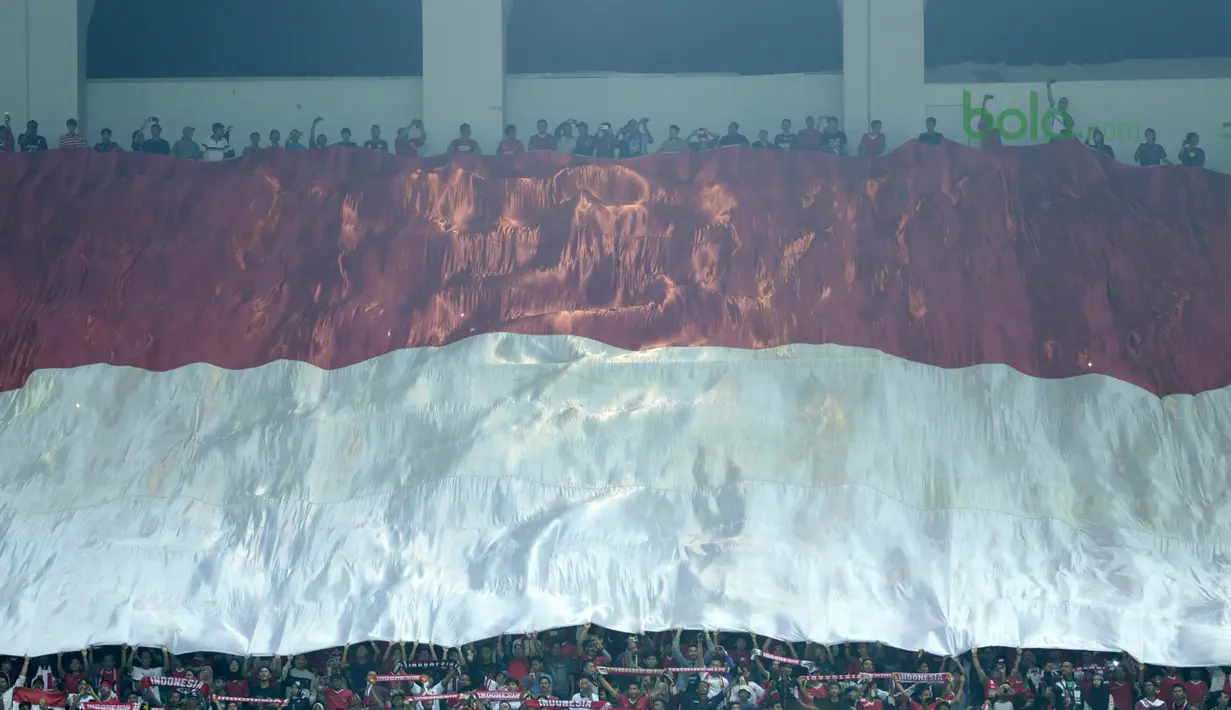 Suporter Indonesia membentangkan bendera raksasa saat laga Timnas Indonesia U-23 melawan Bahrain pada laga PSSI Anniversary Cu 2018 di Stadion Pakansari, Bogor, (26/4/2018). Bahrain unggul sementara 1-0. (Bola.com/Nick Hanoatubun)