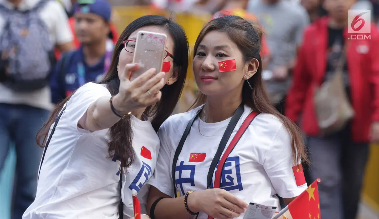 Pendukung tim China berswafoto jelang menyaksikan seremoni pembukaan Asian Games 2018 di Stadion GBK, Jakarta, Sabtu (18/8). Asian Games 2018 akan berlangsung hingga 2 September, mendatang. (Liputan6.com/Helmi Fithriansyah)