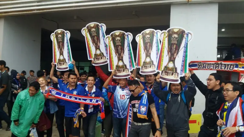 Suporter timnas Thailand membawa poster bergambar trofi Piala AFF 2016