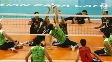 Tim voli duduk putra Indonesia menghadang smash pemain Iraq saat berhadapan pada pertandingan Asian Para Games di GBK, Jakarta, Senin (8/10). Indonesia kalah dari Iraq dengan skor 25-11, 25-10, dan 25-10. (Merdeka.com/Imam Buhori)