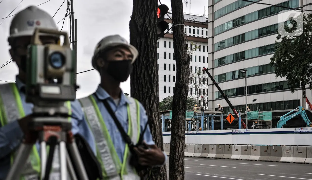 Pekerja mengukur jalan dekat pembongkaran Halte Transjakarta Bank Indonesia di Jalan MH Thamrin, Jakarta, Senin (18/1/2021). Halte tersebut dibongkar untuk kelanjutan proyek MRT Fase 2 CP201 rute Bundaran HI-Harmoni yang ditargetkan rampung pada Maret 2025. (merdeka.com/Iqbal S. Nugroho)