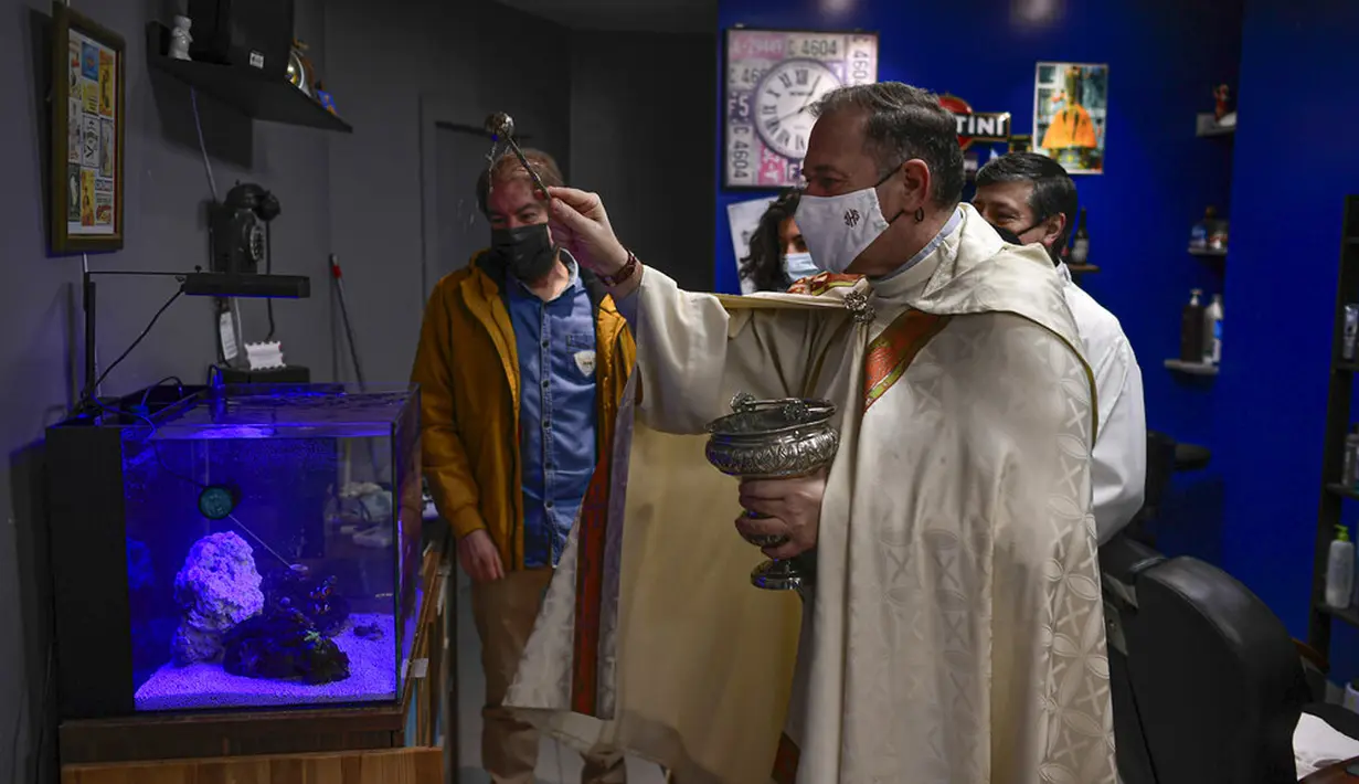 Pendeta Cesar Magana memberkati akuarium kecil di sebuah toko saat pesta Santo Antonius di Pamplona, Spanyol, 17 Januari 2022. Pesta santo pelindung hewan Spanyol ini dirayakan setiap tahun dan orang-orang membawa hewan peliharaan mereka ke gereja untuk diberkati. (AP Photo/Alvaro Barrientos)