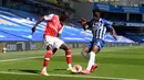 Winger Arsenal, Nicolas Pepe berebut bola dengan pemain Brighton & Hove Albion, Yves Bissouma pada lanjutan pertandingan Liga Inggris di The American Express Community Stadium, Sabtu (20/6/2020). Sempat unggul, Arsenal justru tumbang 1-2 di tangan Brighton. (Mike Hewitt/Pool via AP)