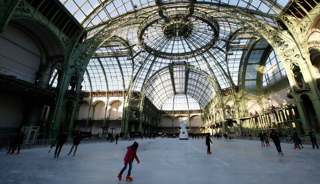 Orang-orang  berseluncur di arena ice skating di bawah kubah kaca mewah legendaris, Grand Palais, Paris, Senin (17/12). Arena ice skating musiman ini terbuka untuk umum selama liburan Natal. (AP Photo/Christophe Ena)