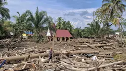 Di tengah duka mendalam akibat banjir bandang dan tanah longsor yang melanda wilayah mereka, umat Protestan tetap menunjukkan keteguhan iman dengan melaksanakan ibadah Natal. Tampak dalam foto, Gereja Protestan Angkola (tengah latar belakang) terlihat di tengah kehancuran akibat banjir di desa Aek Ngadol, Tapanuli Selatan, Sumatera Utara, pada Kamis 25 Desember 2025, setelah banjir dan tanah longsor yang melanda di daerah tersebut pada akhir November 2025 lalu. (AMROE/AFP)