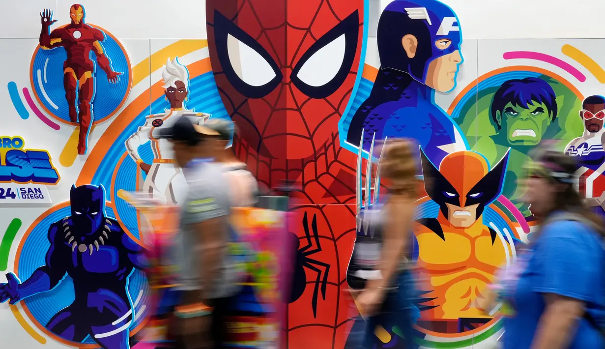 Para peserta konvensi melintasi dinding bergambar karakter superhero Marvel saat malam pratinjau Comic-Con International, Rabu, 24 Juli 2024, di San Diego. (AP Photo/Chris Pizzello)