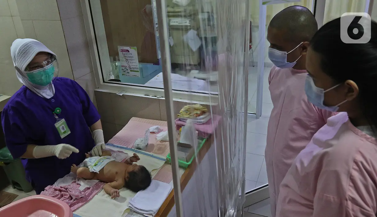 Perawat saat menjelaskan cara memandikan bayi kepada seorang ibu di RSIA Tambak, Jakarta, Kamis (18/02/2021). Melatih para ibu baru untuk memandikan bayi pertama tersebut dilakukan dengan menerapkan protokol kesehatan ketat. (Liputan6.com/Herman Zakharia)