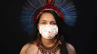 Samela (23) dari kelompok etnis pribumi Sateré Mawé mengenakan pakaian tradisional sukunya dan masker saat pandemi virus corona COVID-19 di Manaus, Brasil, Rabu (27/5/2020). Ibu Samela, Sonia Vilacio pulih dari gejala mirip COVID-19 menggunakan obat alami di rumah. (AP Photo/Felipe Dana)