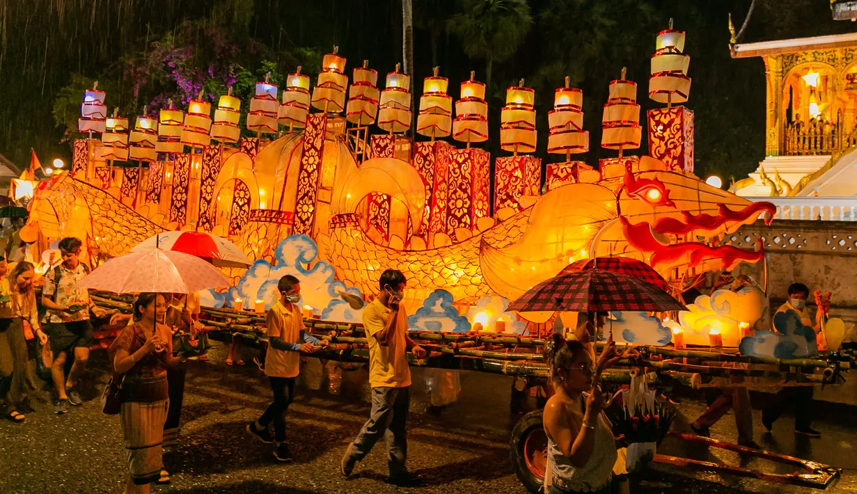 Warga mengikuti parade bersama perahu naga di Luang Prabang, Laos, 3 Oktober 2020. Dalam Festival Boun Lai Heua Fai, warga mendandani kota dengan berbagai lentera, berparade bersama, kemudian melarungkan perahu naga besar dan kecil dari batang pohon pisang ke Sungai Mekong. (Xinhua/Kaikeo Saiyasane)