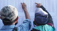 Para warga terdampak perpanjangan PPKM Darurat di Garut, Jawa Barat tengah melihat daftar nama mereka dalam deretan nama yang telah diseleksi Pemda Garut, sebagai penerima bansos tunai Rp 250 ribu per orang. (Liputan6.com/Jayadi Supriadin)