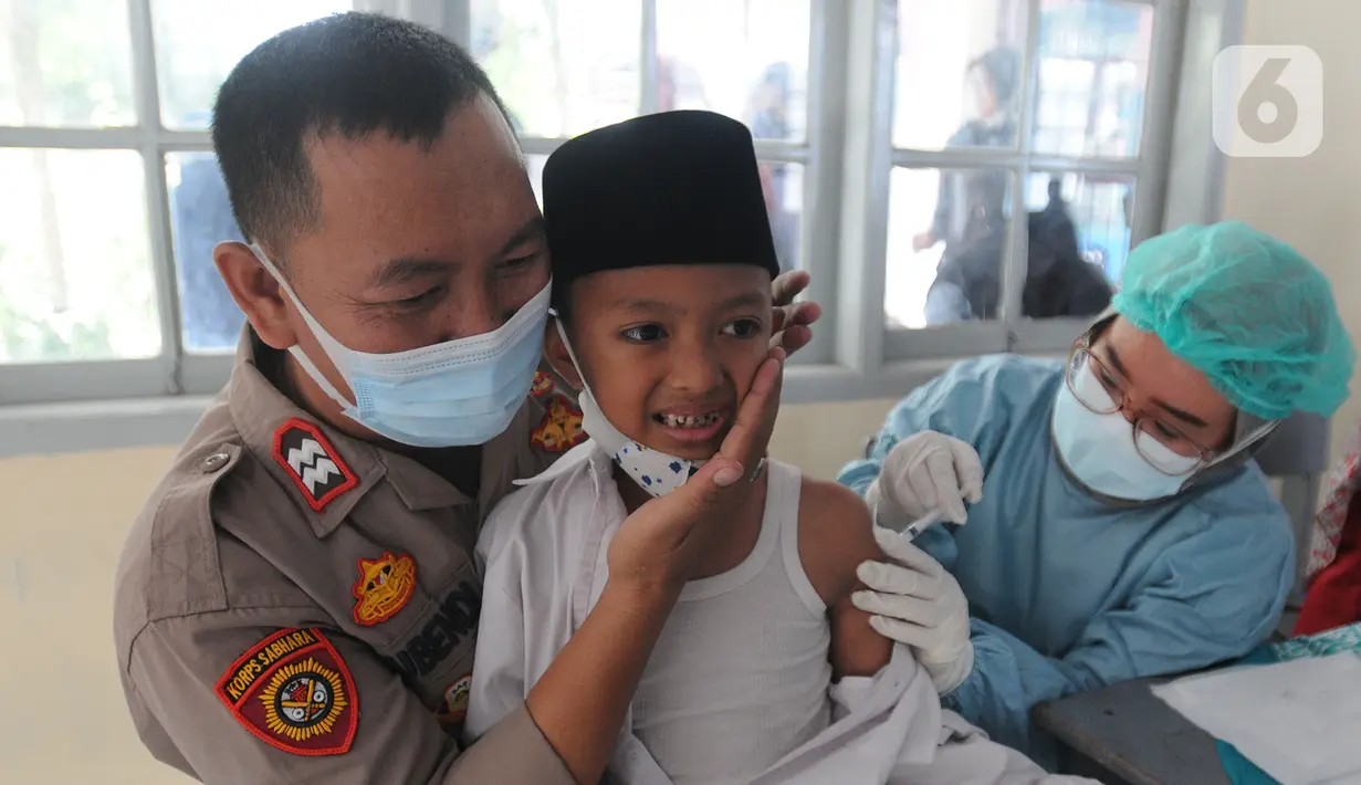 Anggota Polsek Cinere mendampingi murid kelas II saat vaksinasi covid-19 di SDI Al Hidayah, Depok, Selasa (25/1/2022). Mengantisipasi meningkatnya kasus Omicron, pemerintah mempercepat vaksin untuk lansia dan anak-anak, baik itu vaksin dosis pertama, kedua, maupun booster. (merdeka.com/Arie Basuki)
