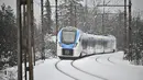 Sebuah kereta penumpang melewati hujan salju di dekat kota Planina, Slovenia, pada Senin (23/1/2023). Hujan salju lebat dan angin kencang menghambat lalu lintas dan menyebabkan pemadaman listrik di seluruh Slovenia. (Jure Makovec / AFP)