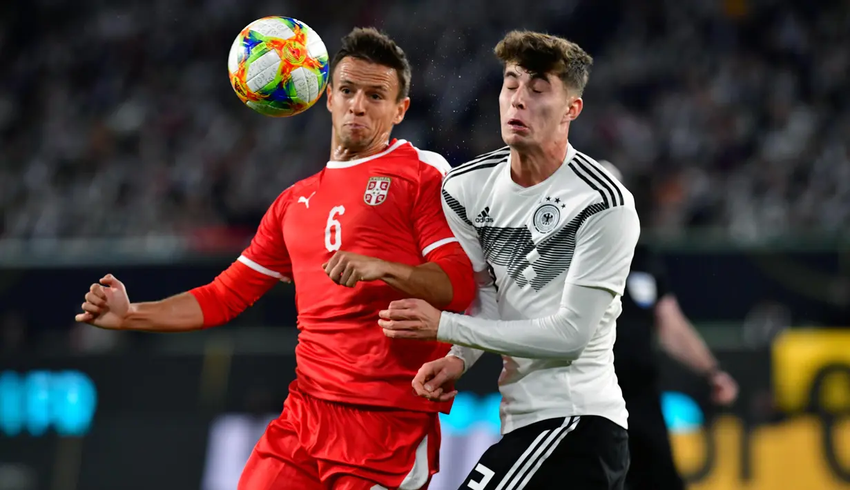 Gelandang Jerman, Kai Havertz, duel udara dengan gelandang Serbia, Nemanja Maksimovic, pada laga persahabatan di Stadion Volkswagen, Rabu, (20/3). Jerman ditahan imbang 1-1 oleh Serbia. (AFP/Tobias Schwarz)