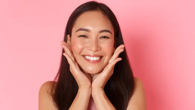 Seorang perempuan tersenyum sambil memegang kedua pipinya (Foto Dok: Freepik/benzoix)