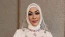 Penampilan Angelina Sondakh di momen pengajian tak kalah memesona. Ia tampil dalam balutan dress brokat putih dengan aksen beads warna pink. Penampilanya dilengkapi dengan hijab segi empat putih dan kerudung senada. [@rezaartameviaofficial/@angelinasondakh09].