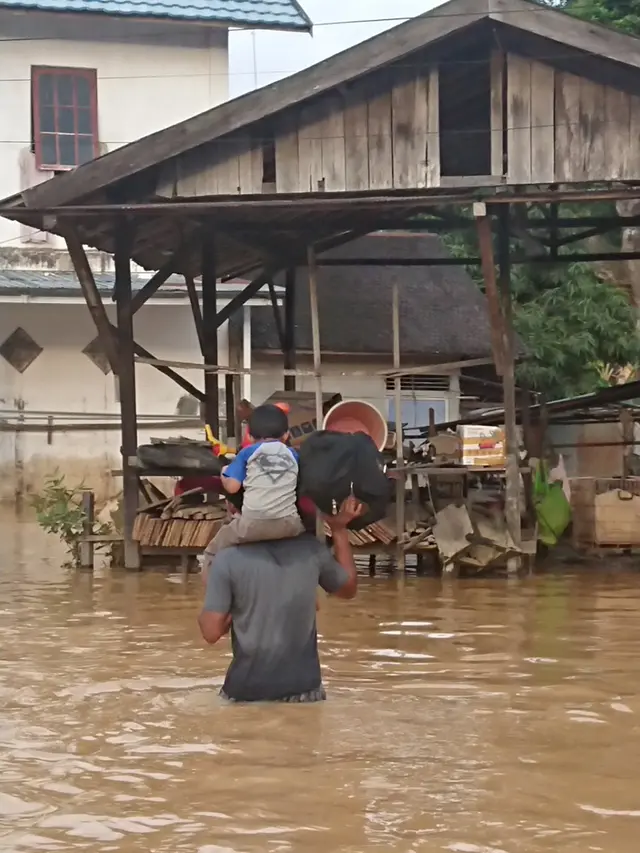 Potret upaya penyelamatan orang tua terhadap anak di tengah banjir.