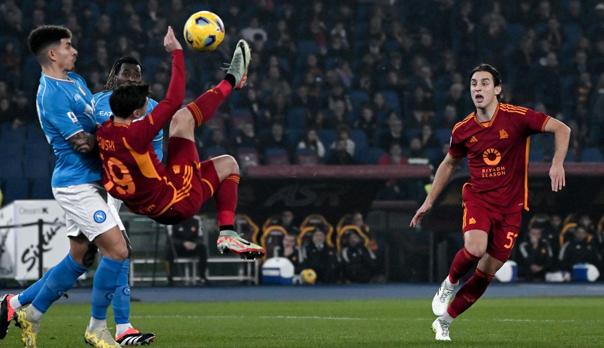 Striker AS Roma, Nicola Zalewski (tengah) berusaha melepaskan tendangan akrobatik di depan bek Napoli, Giovanni di Lorenzo pada laga pekan ke-17 Liga Italia 2023/2024 di Olympic Stadium, Roma, Minggu (24/12/2023) dini hari WIB. (AFP/Tiziana Fabi)