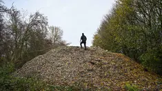 Aktivis lingkungan merekam konten untuk media sosial di tumpukan besar sampah yang dibuang sembarangan, yang ditumpuk di sebuah ladang antara Sungai Cherwell dan Jalan A34 dekat Kidlington, Oxfordshire, di barat London pada 16 November 2025. Gunungan atau tumpukan sampah ilegal berukuran raksasa ditemukan di sebuah ladang di tepi Sungai Cherwell dekat Kidlington, Oxfordshire, Inggris. (Justin TALLIS/AFP)