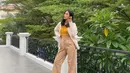 Tampilan kekinian Alika Islamadina dengan kemeja putih sebagai outer dan bandeau top kuning mustard sebagai inner. Untuk bawahan, kamu bisa pilih high waist pants warna nude. (Instagram/alikaislamadina).