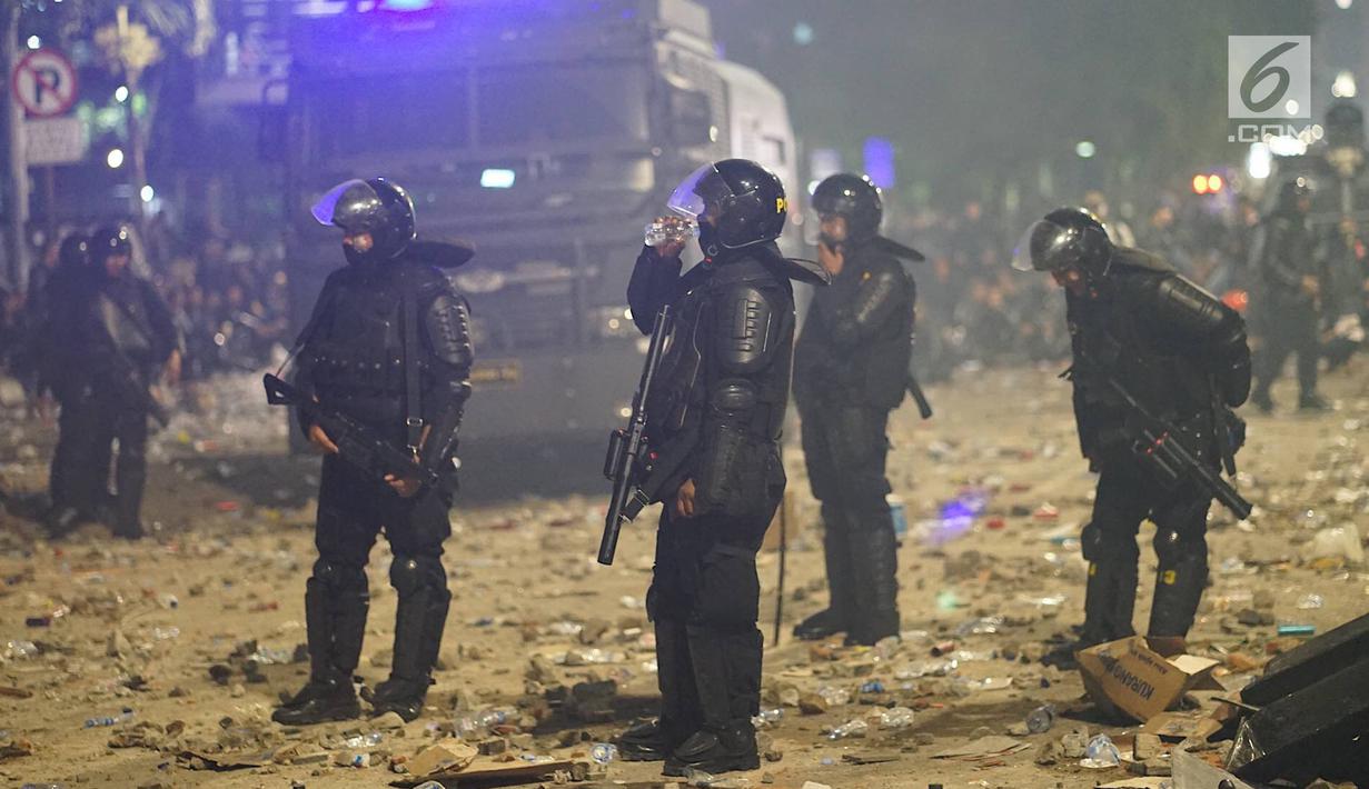 Personel Kepolisian dari satuan Brimob beristirahat sambil minum di sela-sela menghalau massa yang berlaku anarkis di sekitar depan Gedung Bawaslu, Jalan MH Thamrin, Jakarta, Rabu (22/5/2019). Aksi unjuk rasa yang dimotori GNKR berakhir ricuh. (Liputan6.com/Immanuel Antonius)