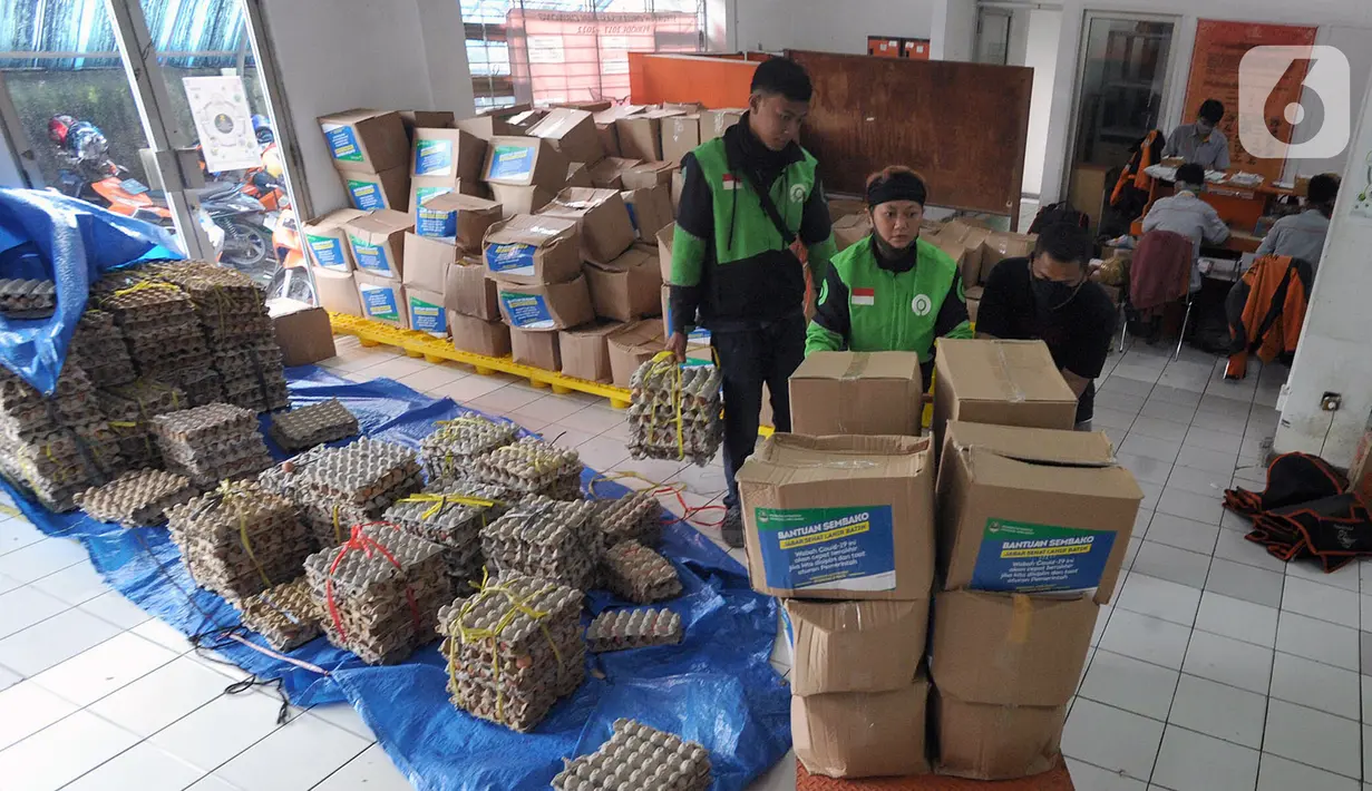 Pengemudi ojek online mengemas bansos untuk warga yang terdampak COVID-19 di Kantor Pos, Cibinong, Bogor, Jawa Barat, Senin (20/4/2020). Bansos khususnya disalurkan di zona merah persebaran yaitu Bogor, Depok, dan Bekasi dengan memberdayakan ojek online. (merdeka.com/Arie Basuki)