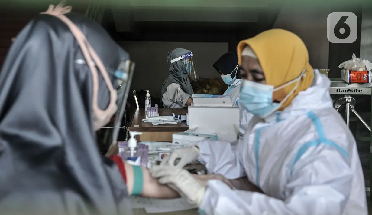 Petugas medis mengambil sampel darah saat rapid test Covid-19 di Stadion Patriot Candrabhaga, Bekasi, Rabu (23/9/2020). Rapid test yang digelar secara gratis oleh Pemkot Bekasi tersebut mampu memeriksa hingga 150 orang tiap harinya guna melacak kasus Covid-19 di Bekasi. (merdeka.com/Iqbal Nugroho)