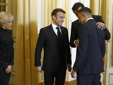 Pemain PSG, Kylian Mbappe (kanan) berbincang dengan Presiden Prancis, Emmanuel Macron (tengah) dan Emir Qatar, Sheikh Tamin bin Hamad Al-Thani (kedua kanan) saat diundang menjadi salah satu tamu di Istana Elysee, Prancis, Selasa (27/2) malam waktu setempat. (AFP/Pool/Yoan Valat)