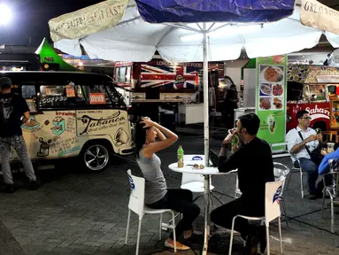 Pengunjung menunggu pesanan makanan yang dijual di atas mobil van di area Food Truck Convoy dalam ajang Indonesia International Motor Show (IIMS) 2015 di JIExpo Kemayoran, Jakarta, Selasa (25/8/2015). (Liputan6.com/Andrian M Tunay)