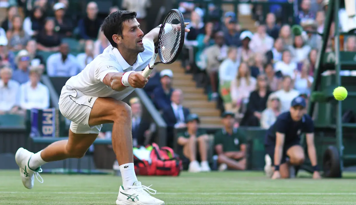 Petenis Serbia, Novak Djokovic mengembalikan bola ke petenis AS, Denis Kudla pada babak kedua Wimbledon di All England Lawn Tennis Club, London, Kamis (4/7/2019) dini hari. Petenis nomor satu dunia itu menang straight set 6-3, 6-2, 6-2 atas Denis Kudla. (Ben STANSALL/AFP)
