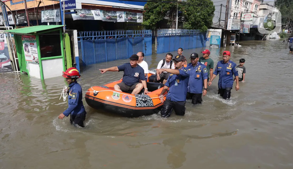 Sejumlah personel pemadam dan penyelamat disiagakan untuk membantu warga melintasi Jalan Raya Cipondoh, Kota Tangerang, Banten yang tergenang air. (Liputan6.com/Angga Yuniar)