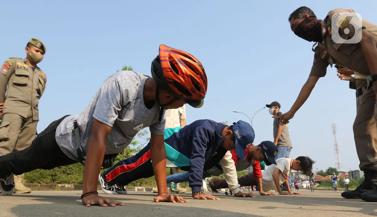 Pelanggar PSBB dihukum push up di kawasan Stadion Pakansari, Kabupaten Bogor, Minggu (6/9/2020). Pemkab Bogor menghukum pelanggar PSBB dengan denda Rp 100 ribu serta sanksi sosial seperti membersihkan area makam, push up, dan mempraktikkan prosesi pemakaman. (Liputan6.com/Herman Zakharia)