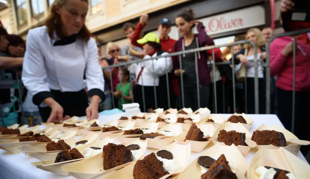 Potongan kue cokelat raksasa atau dikenal sebagai Sacher Torte, yang akan dibagikan kepada pejalan kaki di Ljubljana, Slovenia, Rabu (21/9). Kue cokelat tersebut menghabiskan 2.000 butir telur, 80 kg selai, dan 200 kg cokelat. (AFP PHOTO/Jure MAKOVEC)