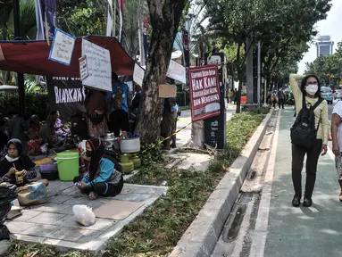 Warga korban gusuran Kampung Bayam mendirikan tenda darurat saat menggelar aksi di depan Balai Kota, Jakarta, Senin (5/12/2022). Dengan membawa terpal dan perabotan rumah tangga, puluhan korban gusuran Kampung Bayam kembali membangun tenda darurat di depan Balai Kota untuk menuntut PT Jakarta Propertindo (JakPro) segera menyerahkan kunci hunian Kampung Susun Bayam (KSB) serta memberikan harga sewa yang murah. (merdeka.com/Iqbal S. Nugroho)