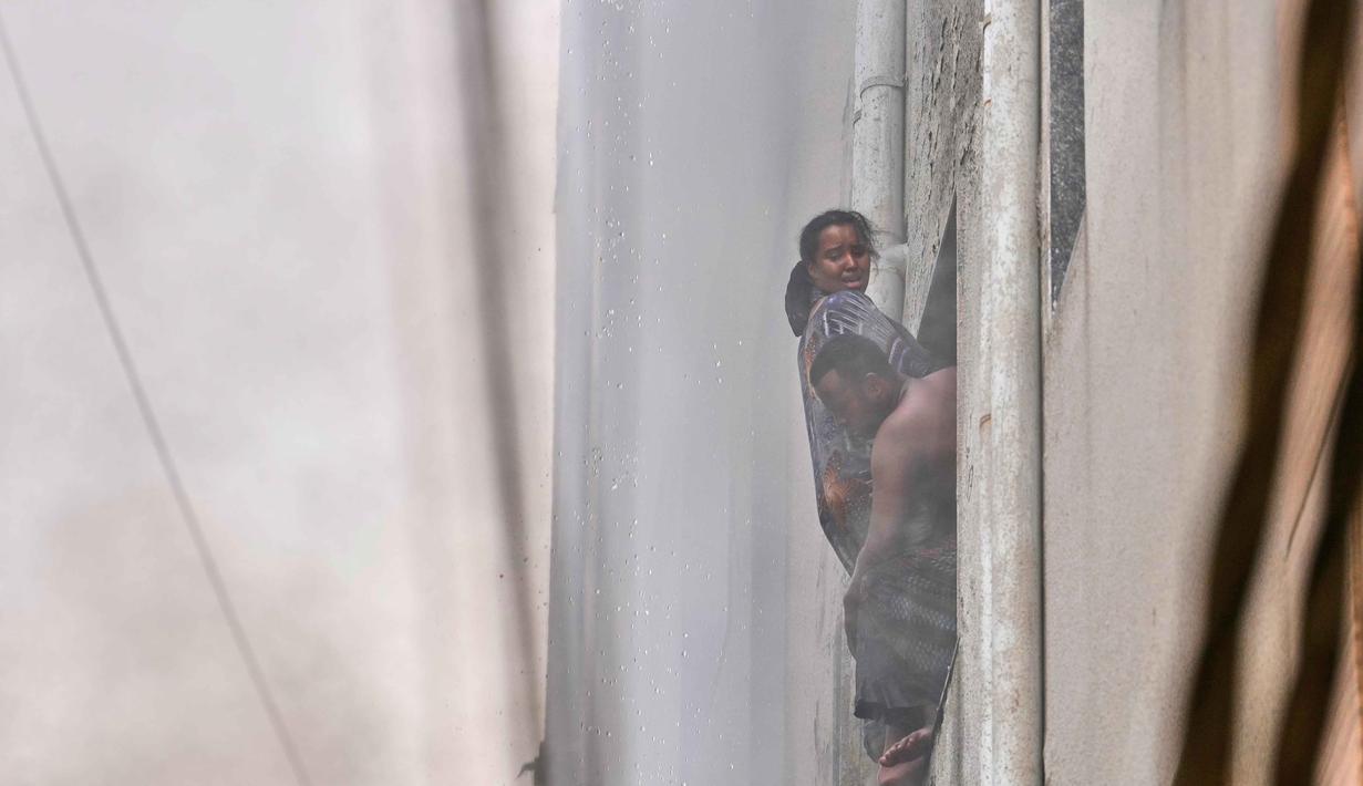Salah satu keluarga warga negara asing tergantung di jendela hotel saat api melalap bangunan sebuah hotel di New Delhi, India, Rabu 3 Juni 2026. (AP Photo/Manish Swarup)