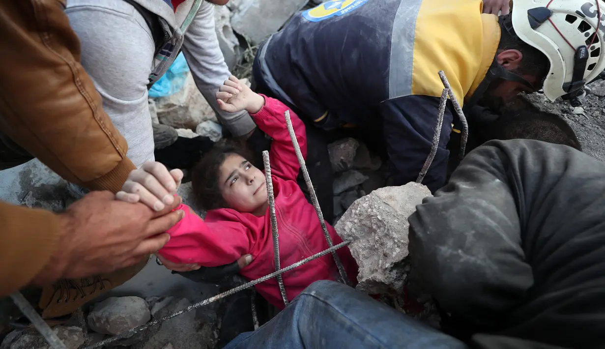 Anggota Syrian Civil Defence atau White Helmets berusaha menyelamatkan gadis yang tertimpa puing bangunan usai serangan udara pasukan pemerintah di Desa Tal Mardikh, Provinsi Idlib, Suriah, Kamis (19/12/2019). Pasukan Suriah kian intens menyerang Idlib. (Omar HAJ KADOUR/AFP)