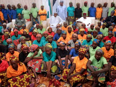 Presiden Nigeria Muhammadu Buhari (tengah) duduk di antara 82 gadis Chibok yang berhasil dibebaskan dari Boko Haram di Presidential Villa di Abuja, Nigeria (7/5). (AFP Photo/PGDBA&HND Mass Communication)