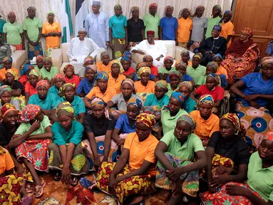 Presiden Nigeria Muhammadu Buhari (tengah) duduk di antara 82 gadis Chibok yang berhasil dibebaskan dari Boko Haram di Presidential Villa di Abuja, Nigeria (7/5). (AFP Photo/PGDBA&HND Mass Communication)