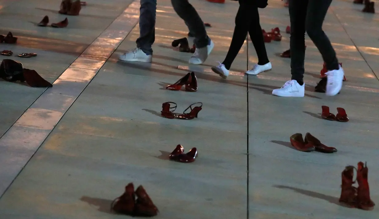 Orang-orang berjalan melewati instalasi ratusan sepatu merah untuk memprotes kekerasan terhadap perempuan di kota pesisir Tel Aviv, Selasa (4/12). Sepanjang tahun ini, 24 perempuan Israel tewas akibat tindakan kekerasan dalam rumah tangga. (JACK GUEZ/AFP)
