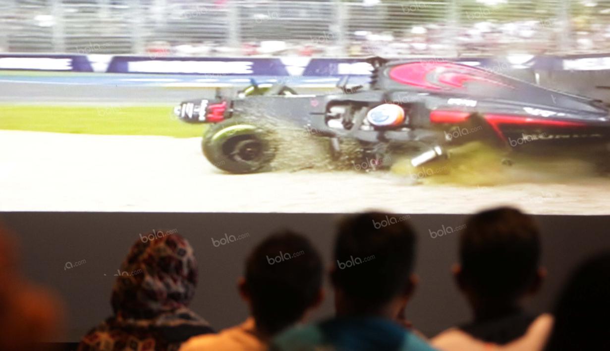 Penggemar Rio Haryanto serius menyaksikan kecelakaan yang menimpa pebalap Fernando Alonso pada balapan Fomula 1 di Resotran Brewerkz, Senayan City, Jakarta, Minggu (20/3/2016). (Bola.com/Nicklas Hanoatubun )