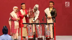 Presiden Joko Widodo memukul alat musik tradisional Batak disaksikan Ibu Negara Iriana Joko Widodo, beserta Ibu Mufida Jusuf Kalla saat membuka pameran Kriyanusa Dewan Kerajinan Nasional 2017, di JCC, Jakarta, Rabu (27/9). (Liputan6.com/Angga Yuniar)