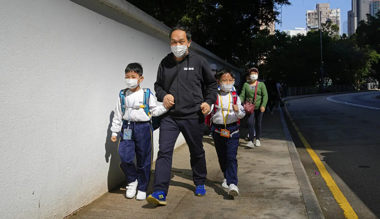 Siswa sekolah dasar berjalan di Hong Kong, Selasa (11/1/2022). Dalam upaya membatasi penularan COVID-19 varian Omicron, Hong Kong mengumumkan penutupan taman kanak-kanak (TK) dan sekolah dasar (SD) setelah infeksi dilaporkan terjadi di kalangan siswa. (AP Photo/Kin Cheung)